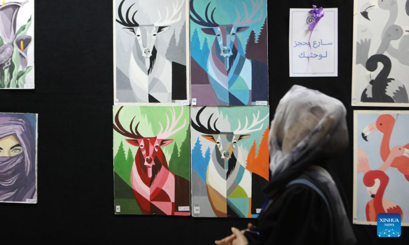 A woman attends an art exhibition organized by Hebron University to support students and market their paintings in the West Bank city of Hebron, on May 3, 2023. (Photo by Mamoun Wazwaz/Xinhua)