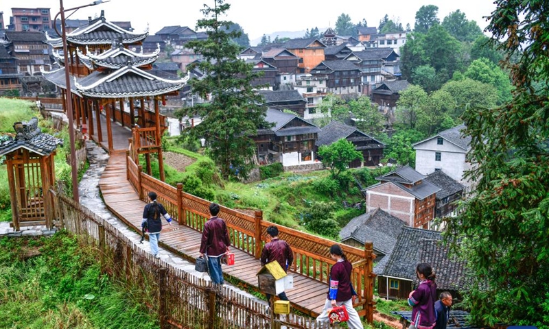 Chorus members walk in a village to visit elderly artists of the song of the Dong ethnic group in Zhaoxing Town of Liping County, southwest China's Guizhou Province, April 23, 2025.（Photo: Xinhua)